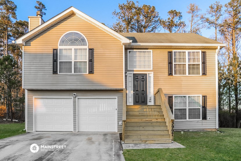 a yellow and with a front porch and a driveway