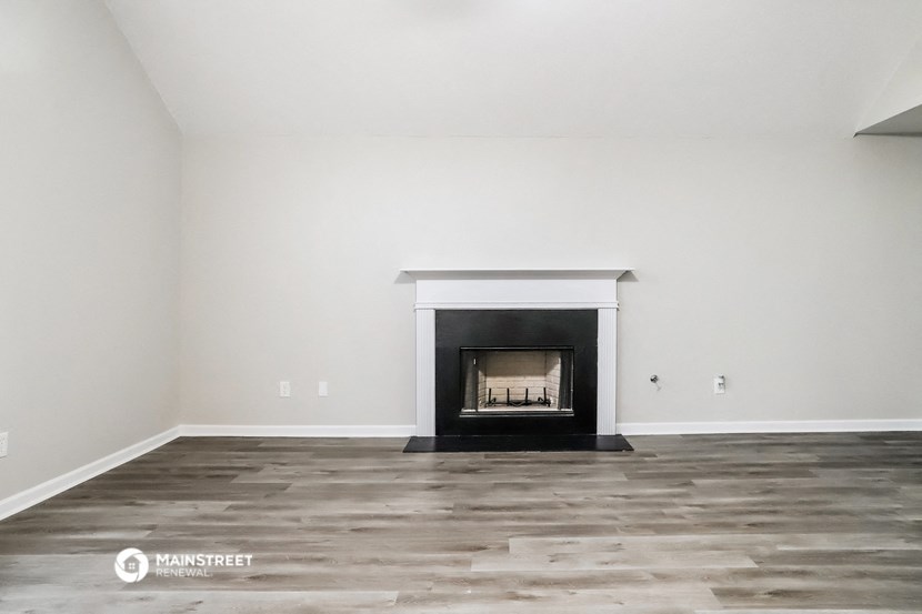 the living room has a fireplace and wooden floors