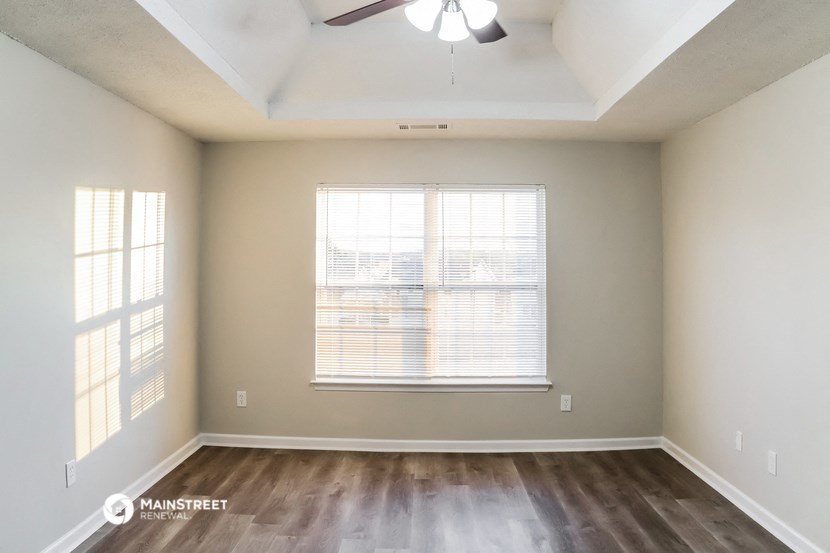 an empty living room with a window and a ceiling fan