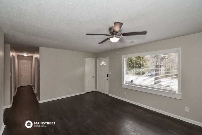 an empty living room with a ceiling fan and a window