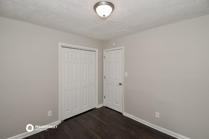 the living room of an apartment with two doors and a closet