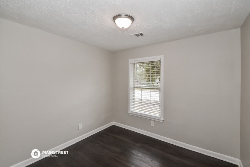 the interior of an empty room with wood flooring and a window