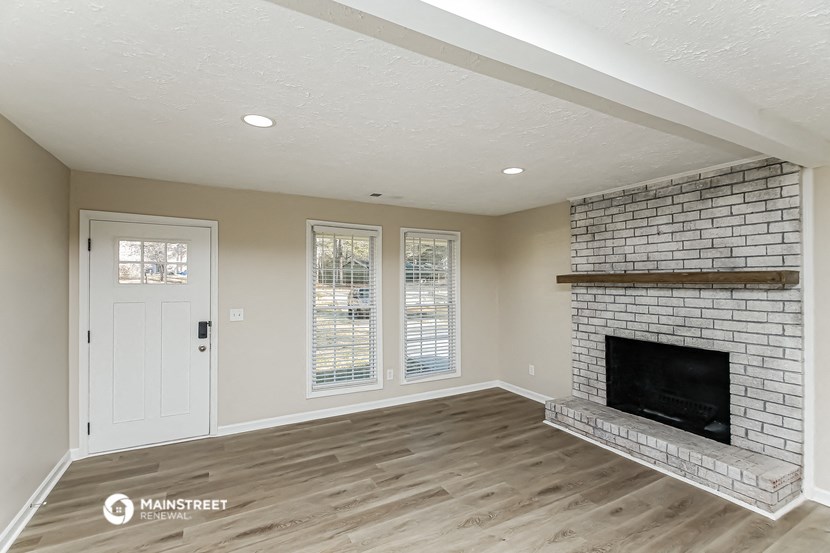 a living room with a brick fireplace and a white door