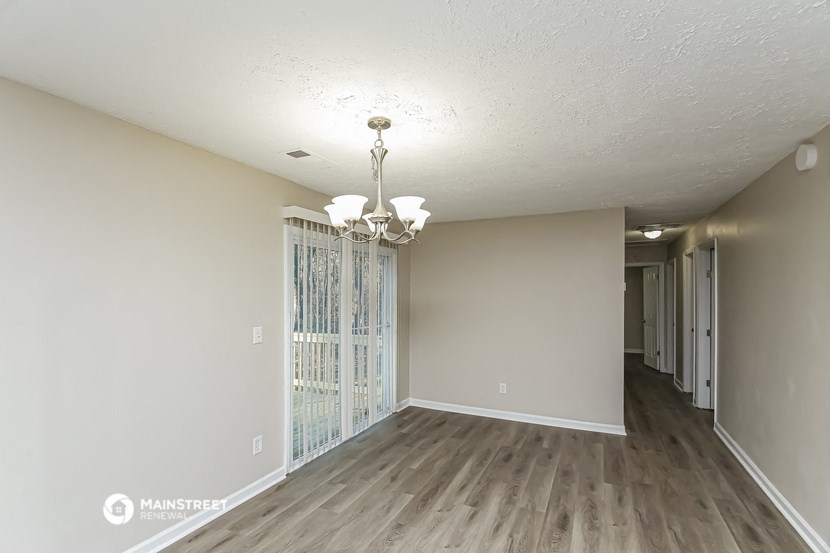 an empty living room and hallway with wood floors and a chandelier