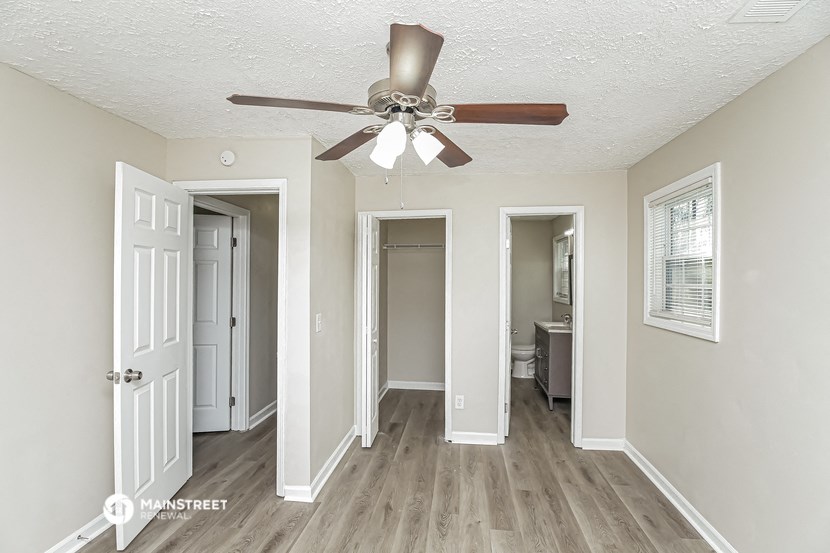 a living room with a ceiling fan and a door to a bathroom