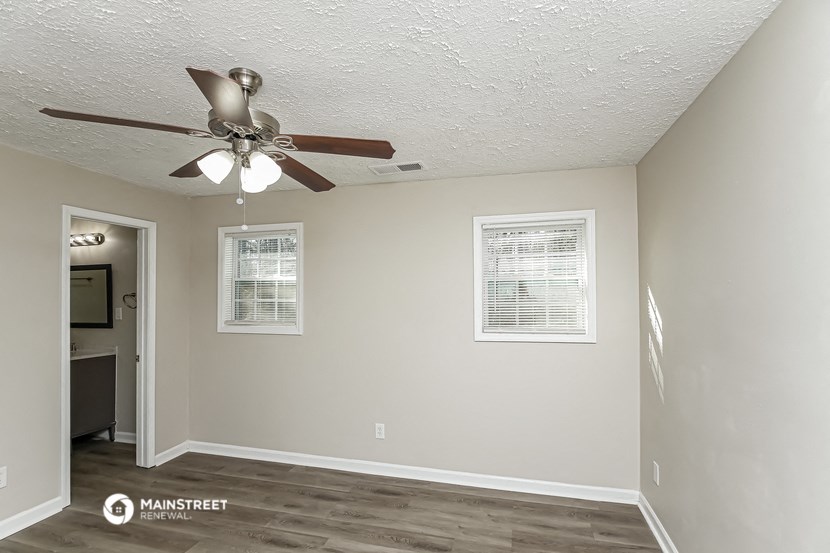 a living room with a ceiling fan and a door to a kitchen