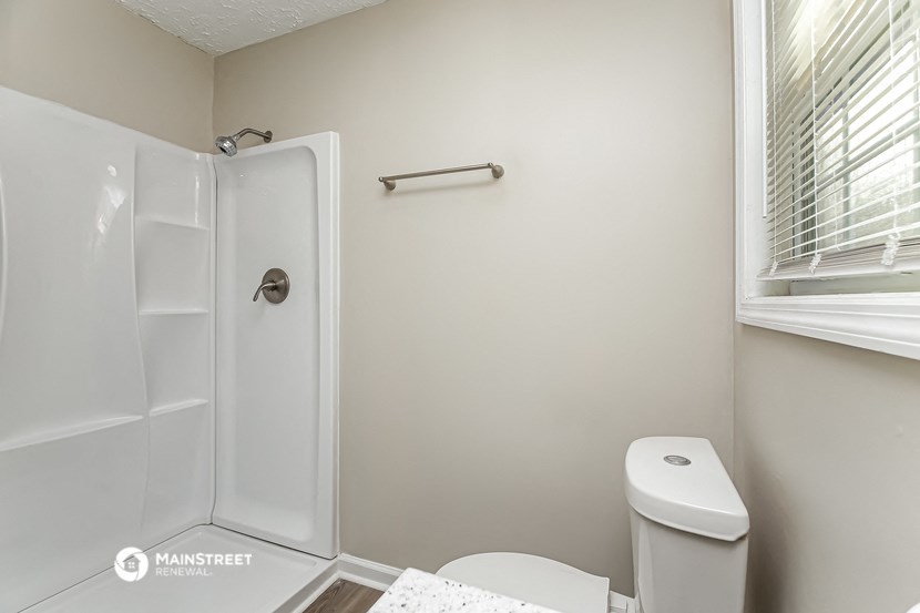 a white bathroom with a white toilet and a shower