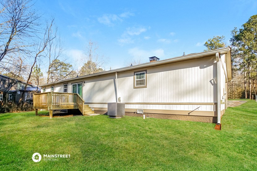 a small white house with a deck and a grassy yard
