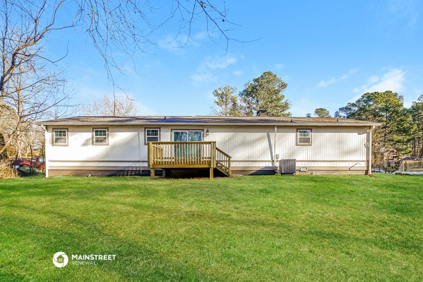 a white mobile home with a deck and a grassy yard