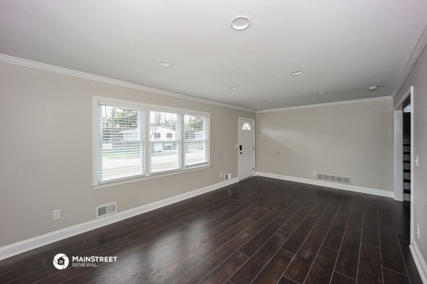 the living room of a house with wood floors and a large window