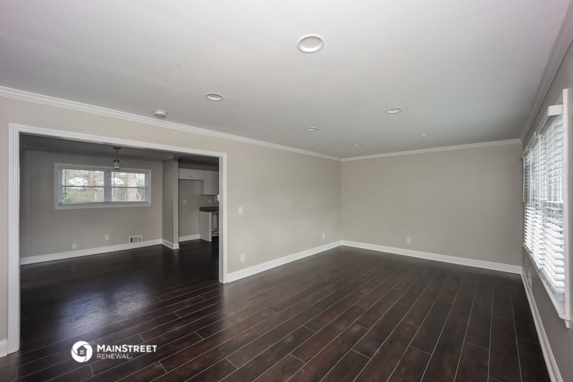 an empty living room with wood floors and white walls