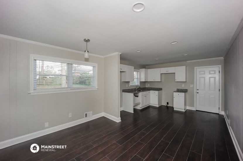 an empty kitchen with white cabinets and a large window