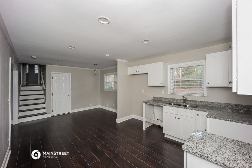 a kitchen with white cabinets and granite counter tops and dark wood floors