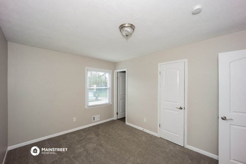 the living room of a manufactured home with a door to the closet and a window