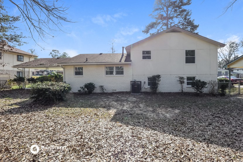 a white house with a gravel driveway and a yard with trees