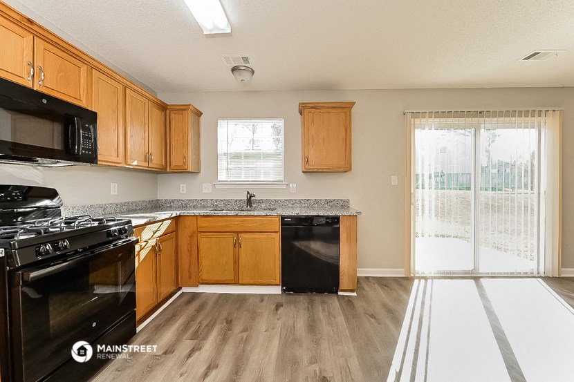 a kitchen with wood cabinets and black appliances and a sliding glass door