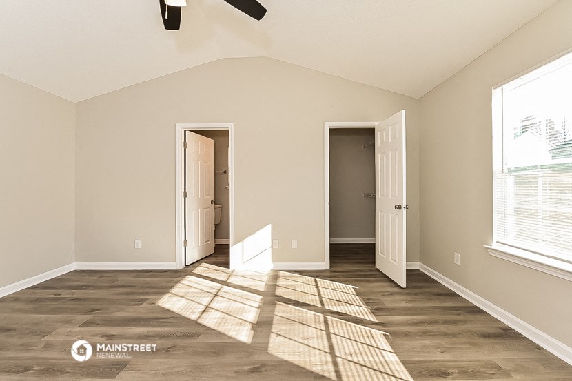 the spacious living room with a large window and a door to the bathroom