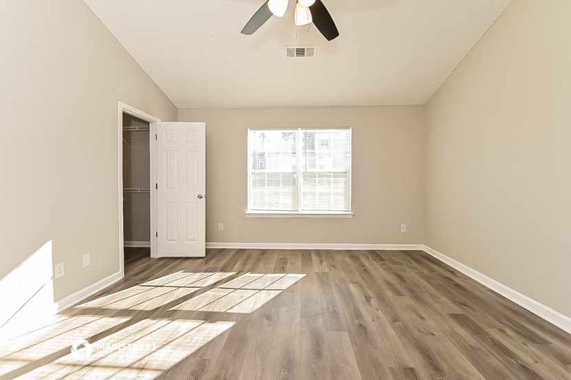 an empty living room with hardwood flooring and a window