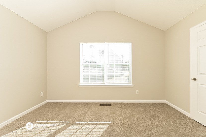 a bedroom with a window and carpeted floor