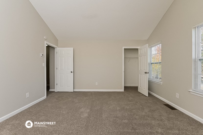 the living room of an apartment with a carpeted floor and two doors