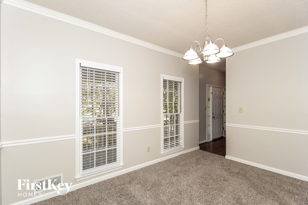 a spacious living room with windows and a door to a hallway