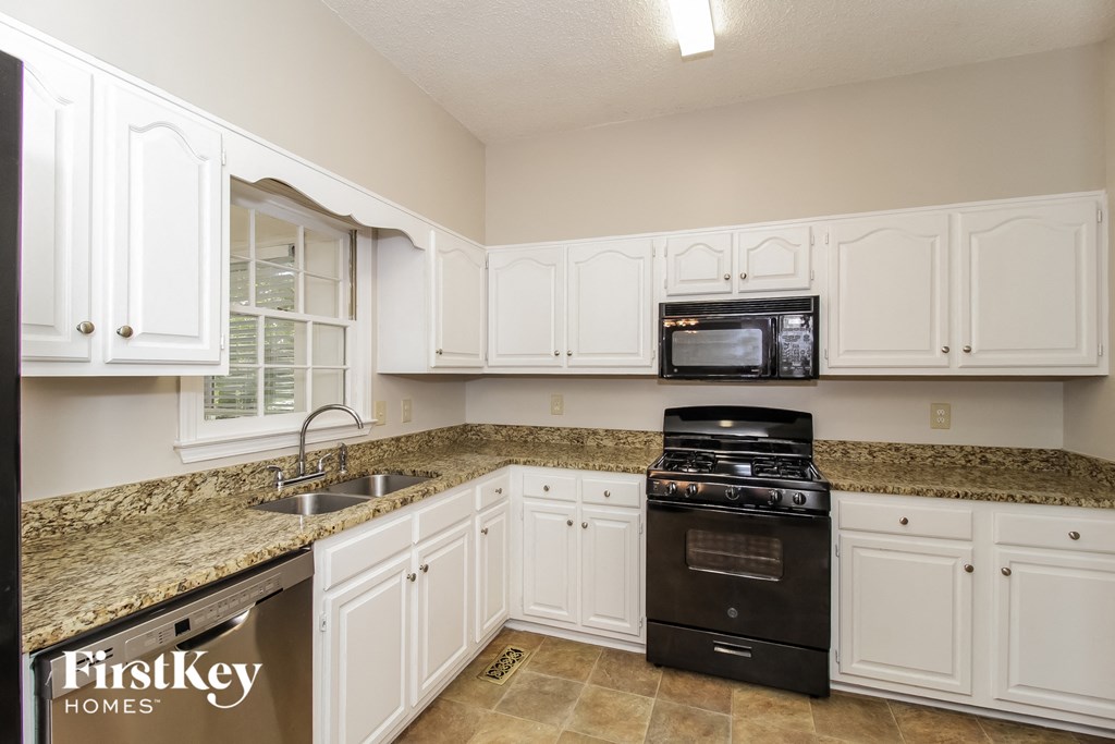 a kitchen with white cabinets and granite counter tops and black appliances