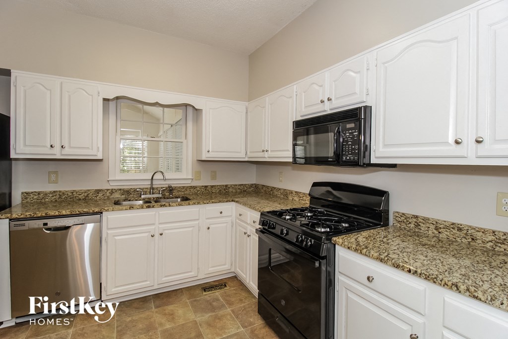 a kitchen with white cabinets and black appliances