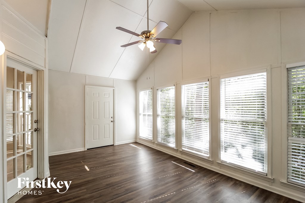 an empty living room with large windows and a ceiling fan