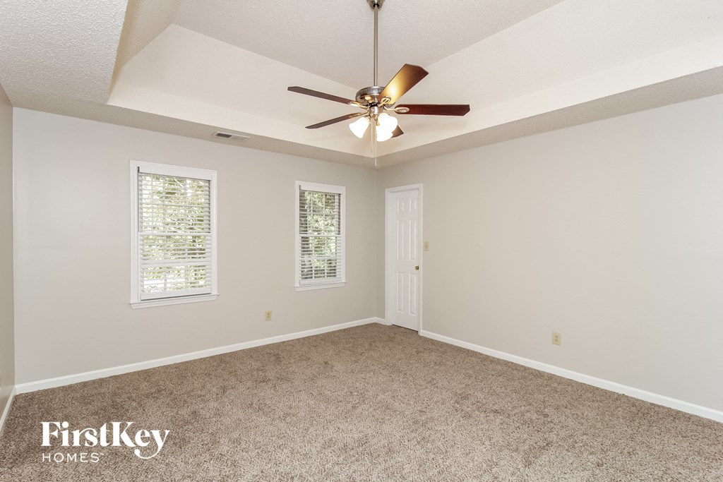 the master bedroom has a ceiling fan and a carpeted floor