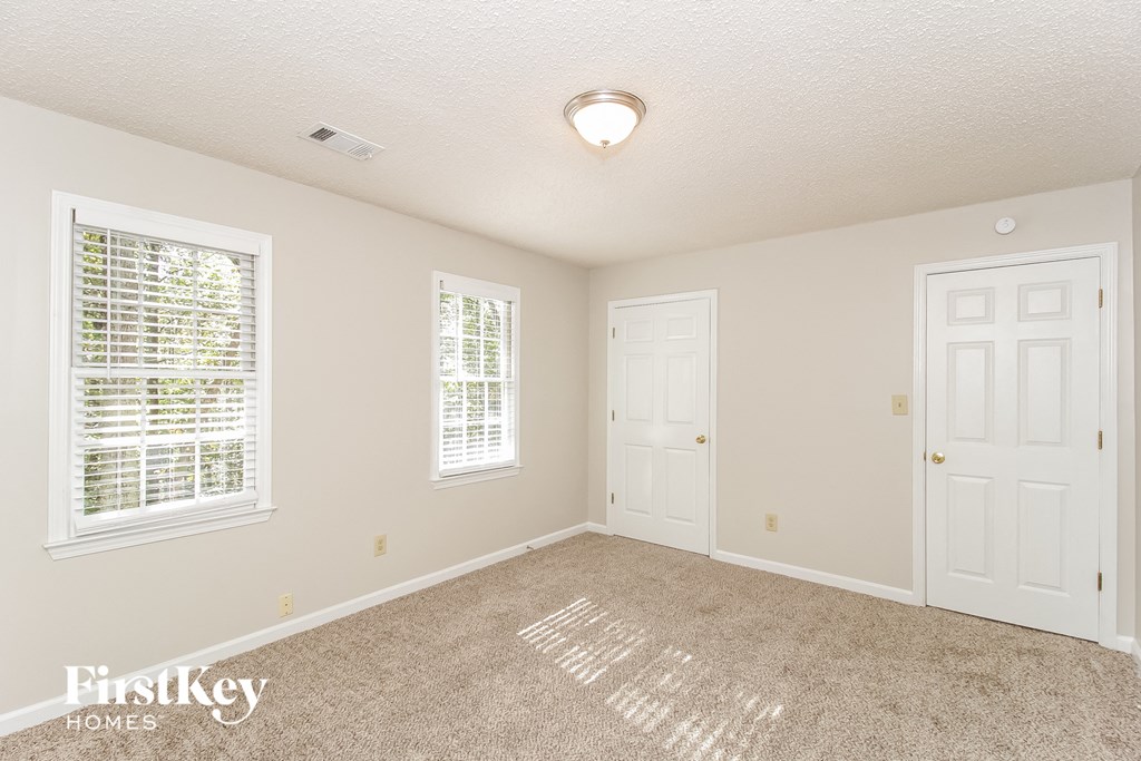 a spacious bedroom with two doors and a carpeted floor