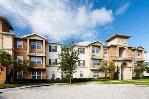 A large apartment complex with a parking lot in front.