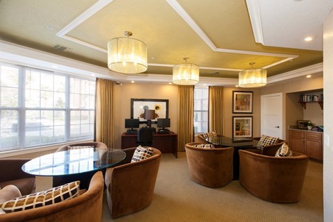 A living room with a glass table and brown chairs.