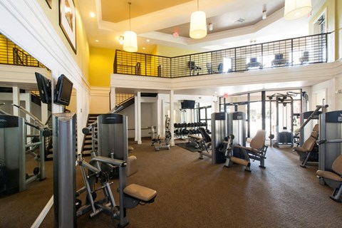 A gym with a variety of equipment including treadmills, weights, and exercise machines.