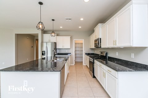 A kitchen with white cabinets and a black countertop.