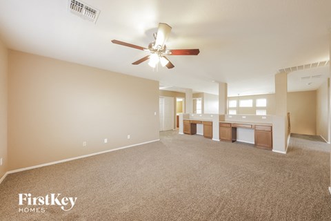 A spacious room with a ceiling fan and beige walls.