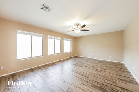 A spacious room with wooden flooring and a ceiling fan.