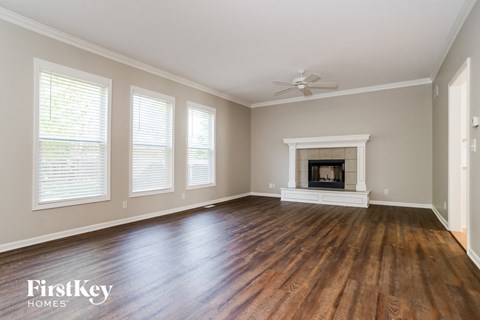 A spacious room with a fireplace and wooden floors.
