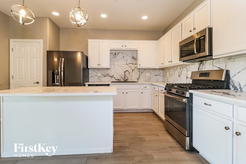 a kitchen with white cabinets and stainless steel appliances and marble counter tops