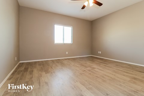 the spacious living room with wood flooring and a ceiling fan