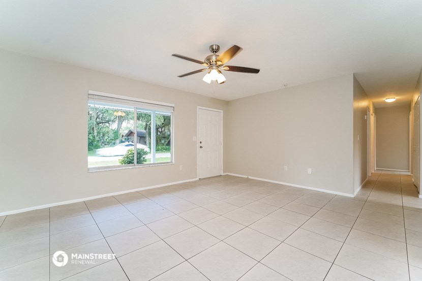 an empty living room with a ceiling fan and a large window
