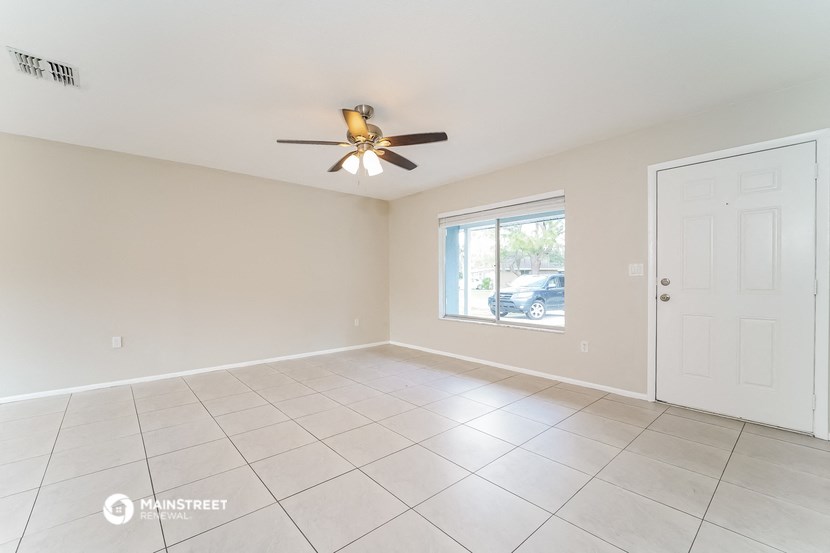the living room of an empty home with a ceiling fan