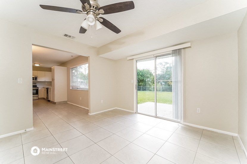 an empty living room with a ceiling fan and sliding glass doors
