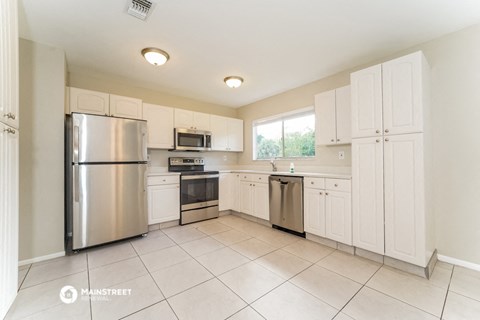 a large kitchen with stainless steel appliances and white cabinets