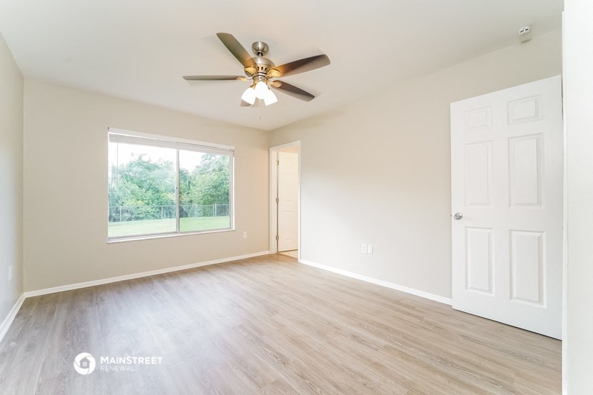an empty living room with a ceiling fan and a window