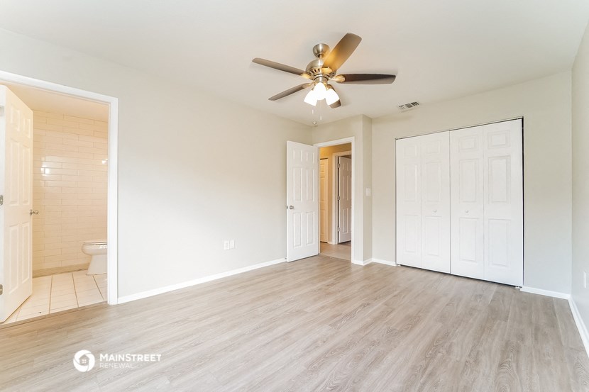 a living room with a ceiling fan and a door to a bathroom