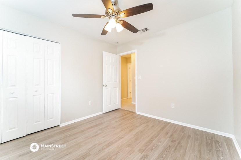 the living room of an empty house with a ceiling fan