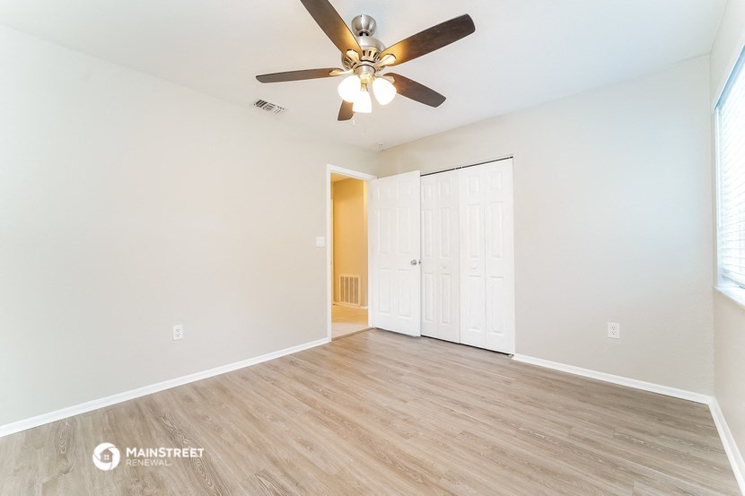 an empty living room with a ceiling fan and a closet