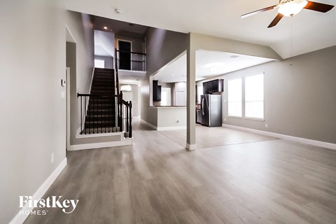 an empty living room with a staircase and a ceiling fan