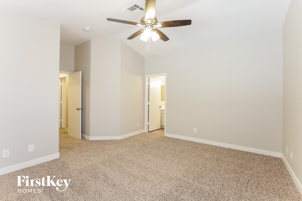 a master bedroom with carpet and a ceiling fan