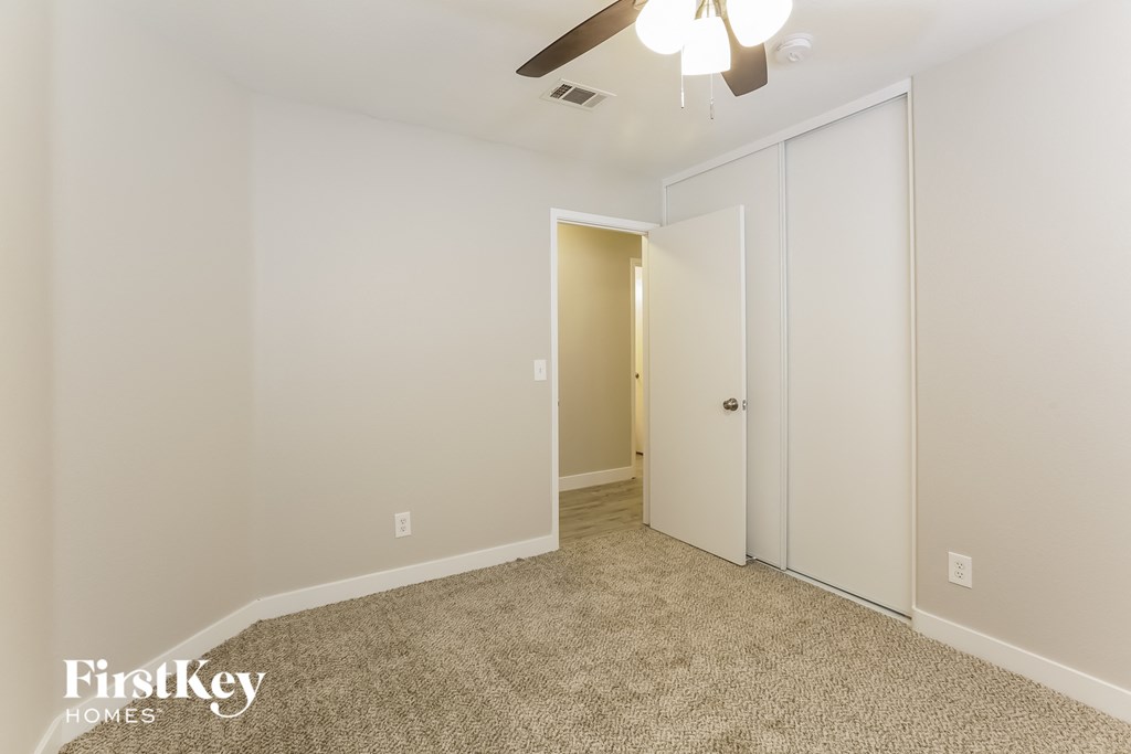 a bedroom with white walls and a ceiling fan